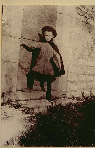 Marcel Aymé rentrant de l'école, à la porte de la cuisine de la ferme de la tuilerie vers 1909.