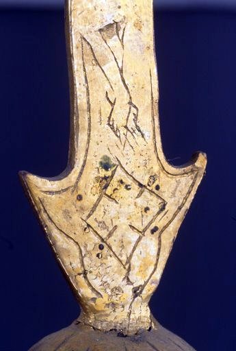 Détail du bas de la croix sommitale, à l'avers : jambes du Christ en croix, gravées.