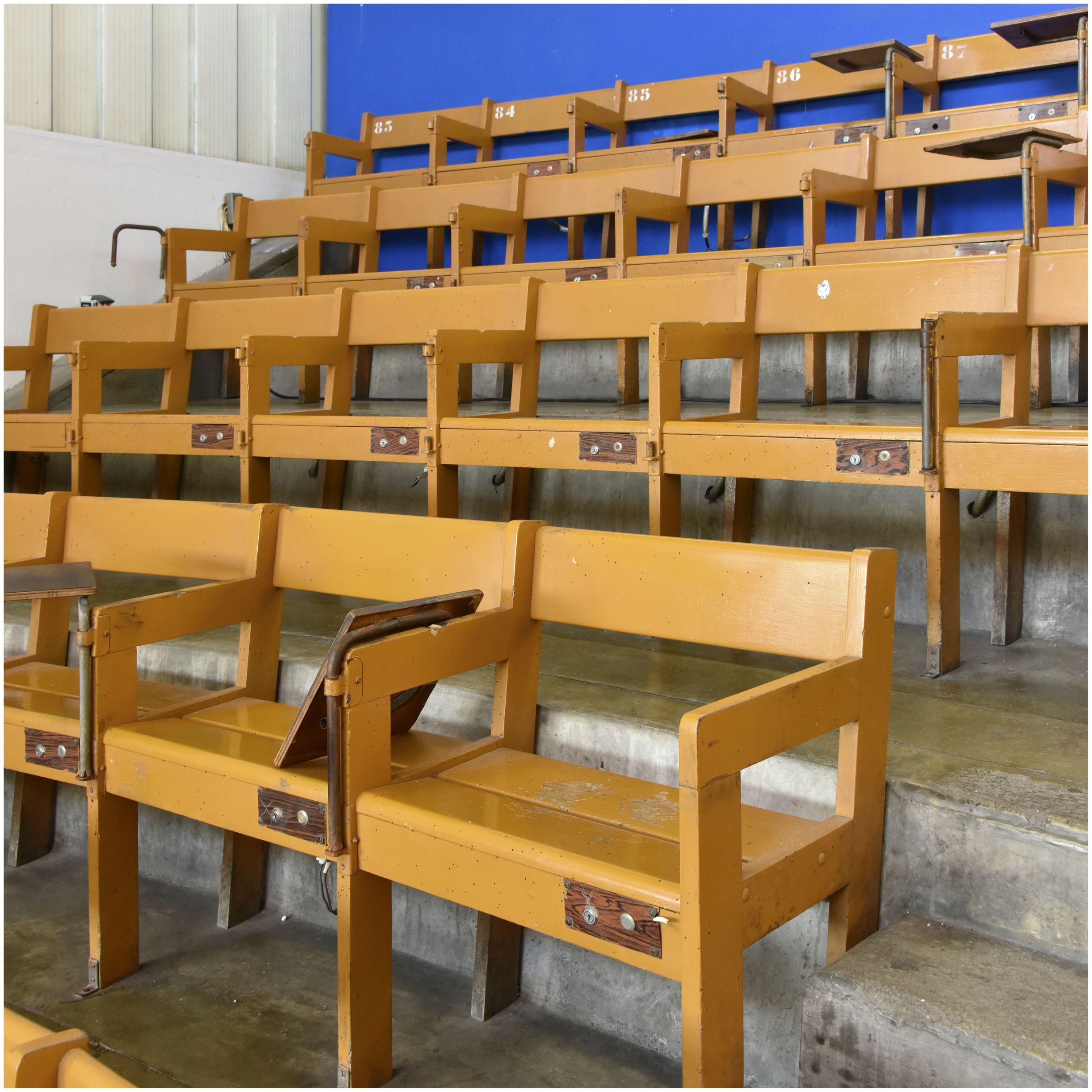 Salle de la criée. Siège en bois avec tablettes et prises électriques.