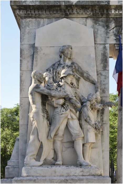 Groupe sculpté de droite. La patrie rend hommage aux morts : une petite fille en civil, un soldat casqué et un homme torse nu apportent des fleurs et du laurier, ils sont dominés par une figure  désignant l’entrée de la crypte.