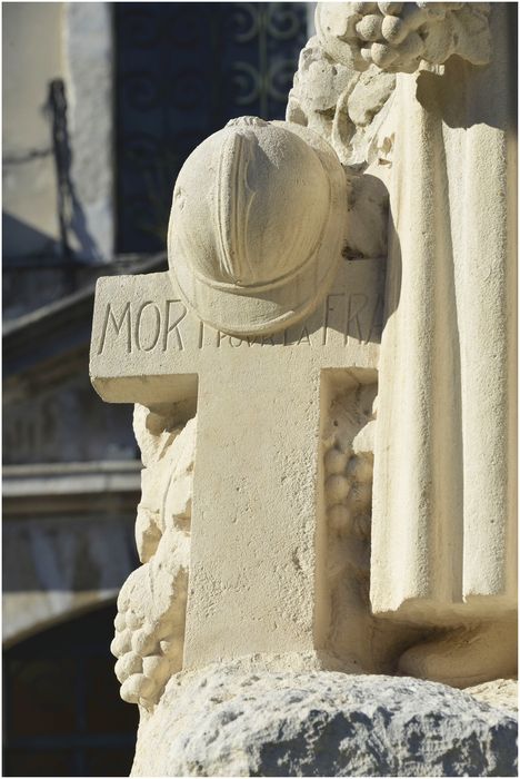 Groupe sculpté. Vue latérale. Croix et casque. Détail.