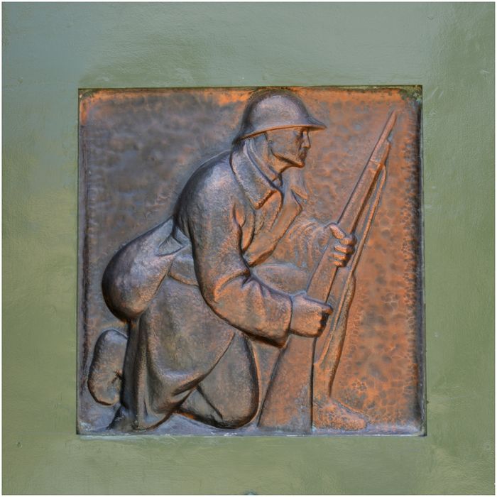 Portail de gauche. Bas-relief. Soldat agenouillé tenant un fusil.