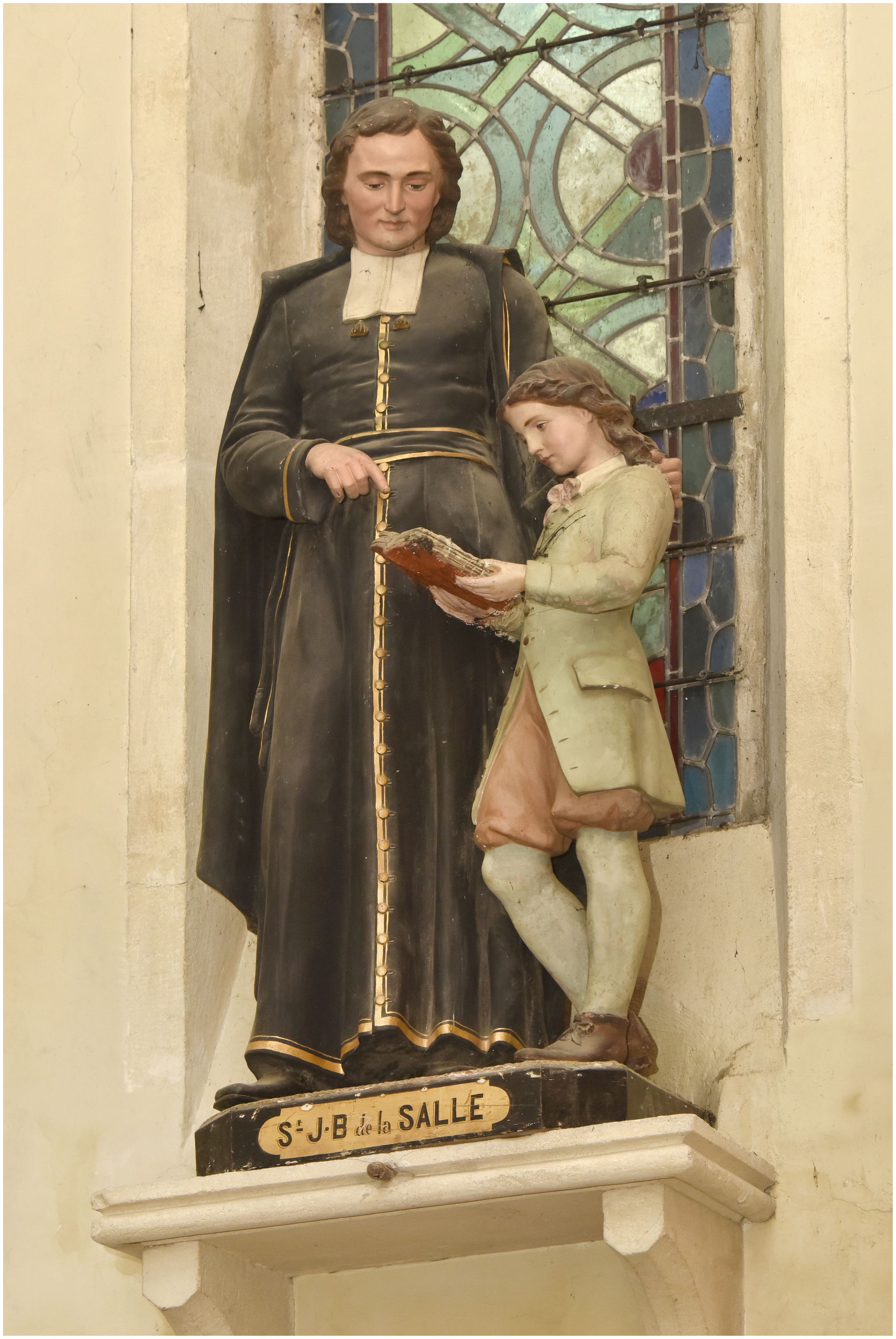 Statue de saint Jean-Baptiste de la Salle enseignant à un jeune garçon.