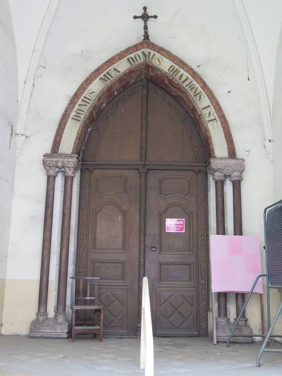 Porte d'entrée de la chapelle, entourée de doubles colonnettes en bois posées sur des chapiteaux en remploi.