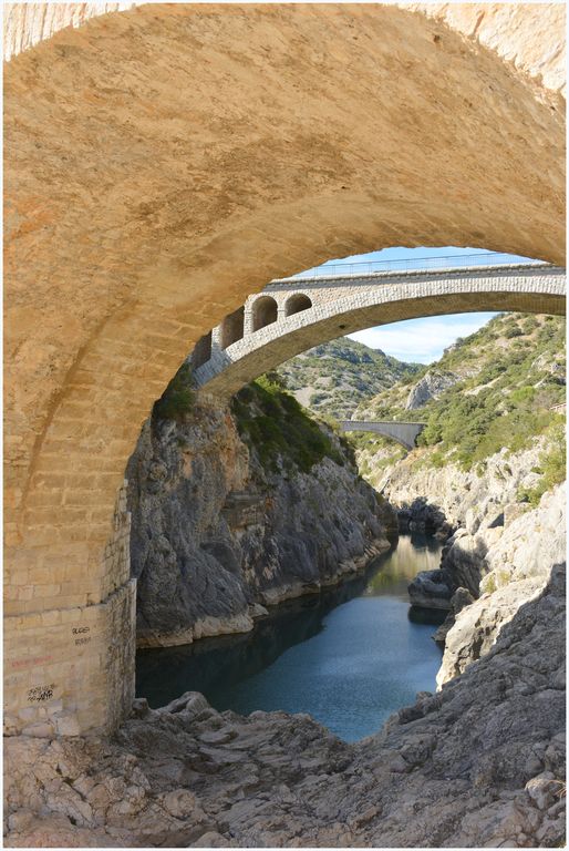 Vue sous une arche du pont, vers l’amont et le pont  en béton armé.