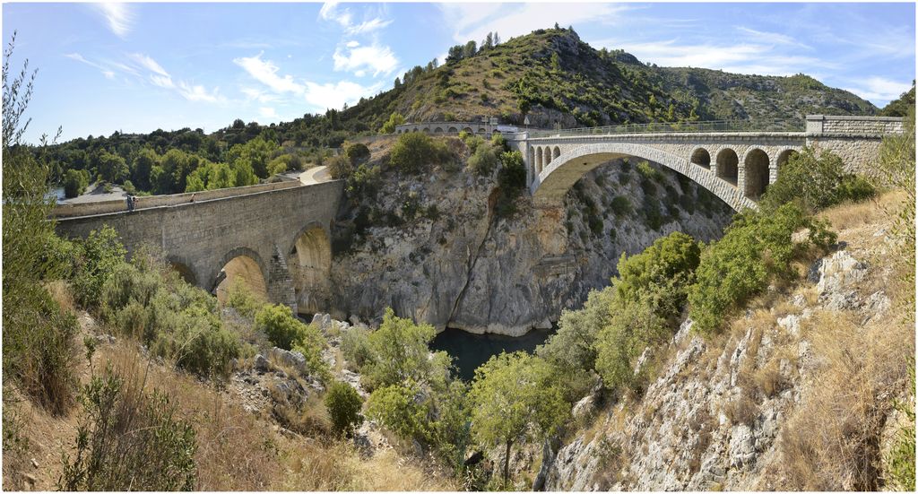 Vue d’ensemble du pont prise de l’amont, avec le pont en béton armé sur lequel passe la route.