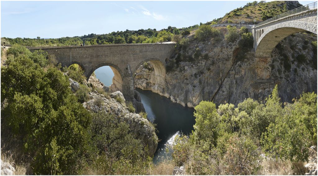 Vue d’ensemble du pont prise de l’amont, avec le pont  en béton armé sur lequel passe la route.