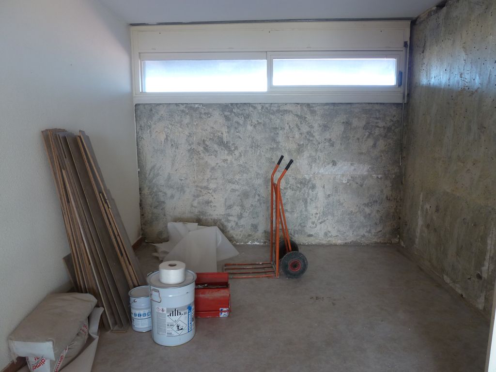 Appartement en travaux : pièce traversante éclairée à l’est par des ouvertures horizontales en hauteur, prenant jour sur la coursive.