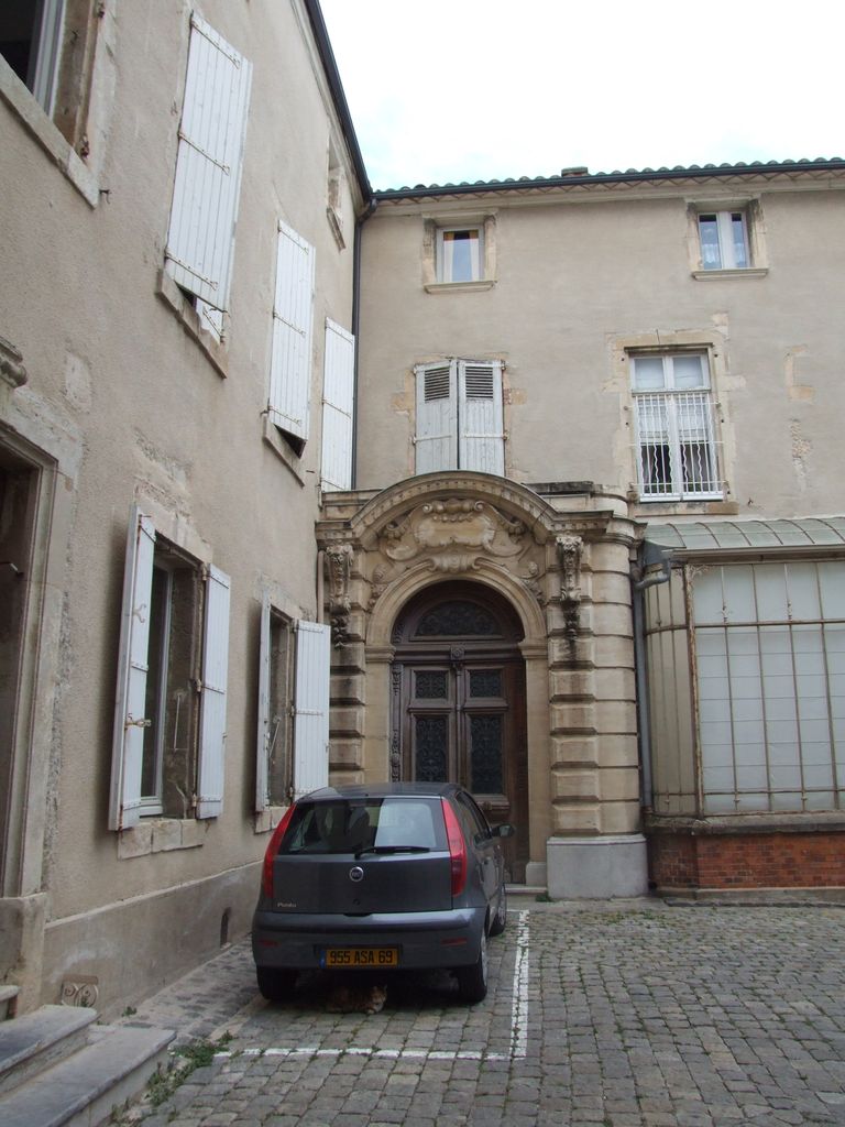 Cour intérieure. Hôtel du 19e siècle, porte à fronton curviligne donnant accès au grand escalier.