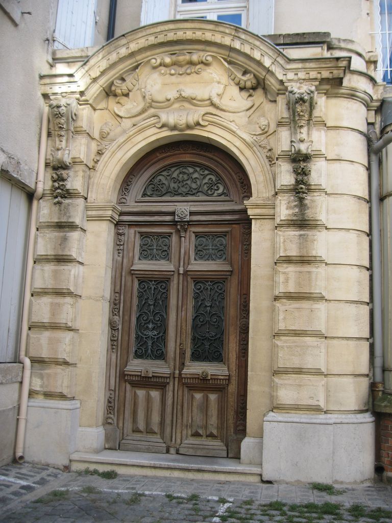 Cour intérieure. Hôtel du 19e siècle, porte à fronton curviligne donnant accès au grand escalier.