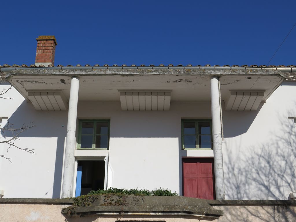 Façade sur la cour de récréation. Sortie des élèves dans la cour protégée par un auvent.