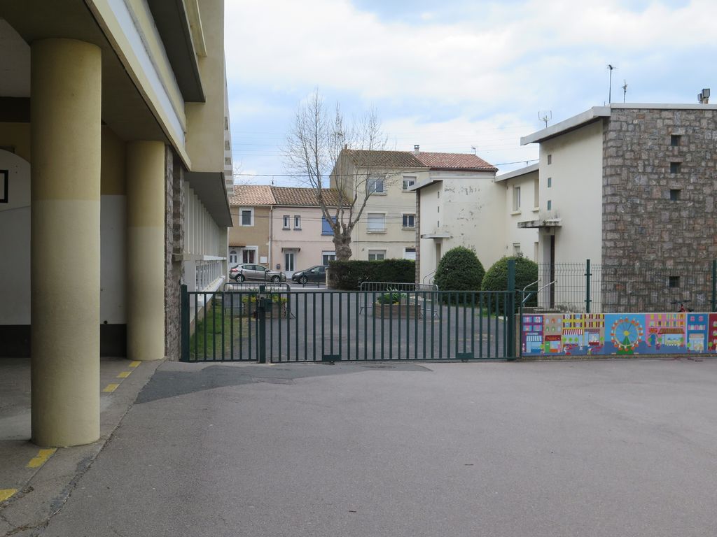 Depuis le groupe scolaire, vue des logements à droite et de la cantine à gauche. Au premier plan, le préau.