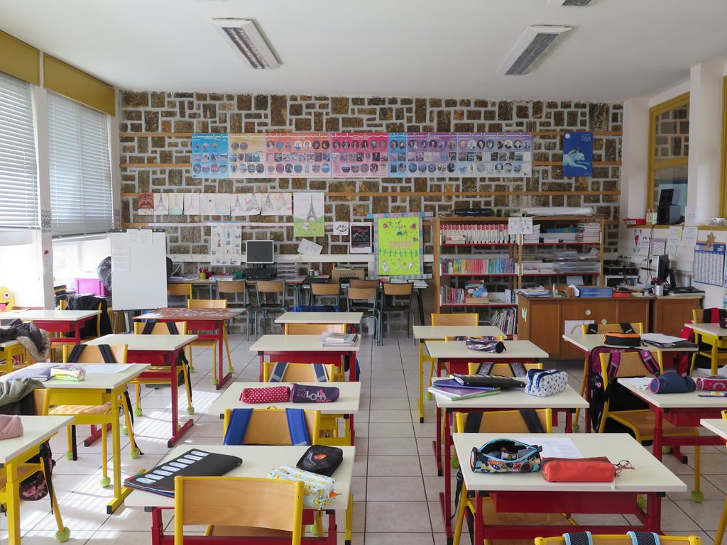Salle de classe dont un des murs est en appareil de pierre.