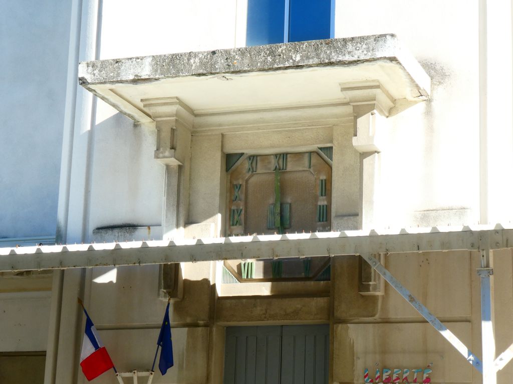 Pavillon d’entrée. Horloge protégée par un auvent débordant en béton.