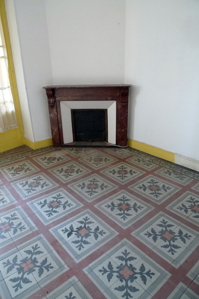 Cheminée et sol en carreaux-ciment d'une pièce de l'appartement.