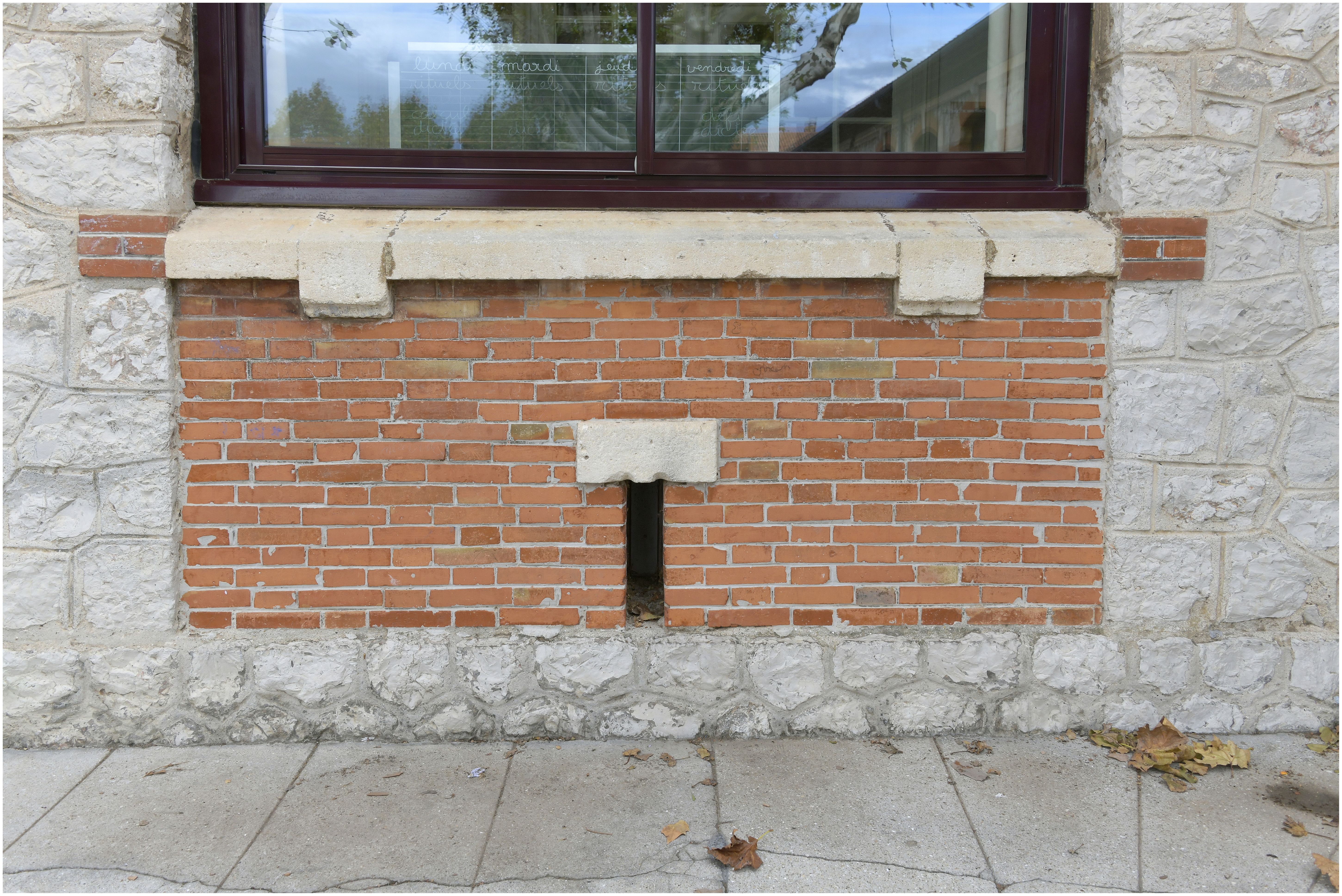 Façade sur cour. Détail du parement et de l’appui de fenêtre en pierre encadrant un appareil de briques 