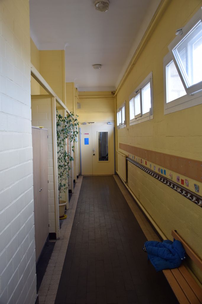 Ecole maternelle. Couloir avec sol en céramique marron foncé et bordure.