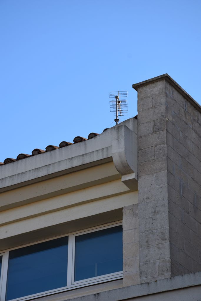 Ecole élémentaire Jean-Moulin. Façade sur rue. Détail des parements pierre et moulures et corniche en béton lisse.