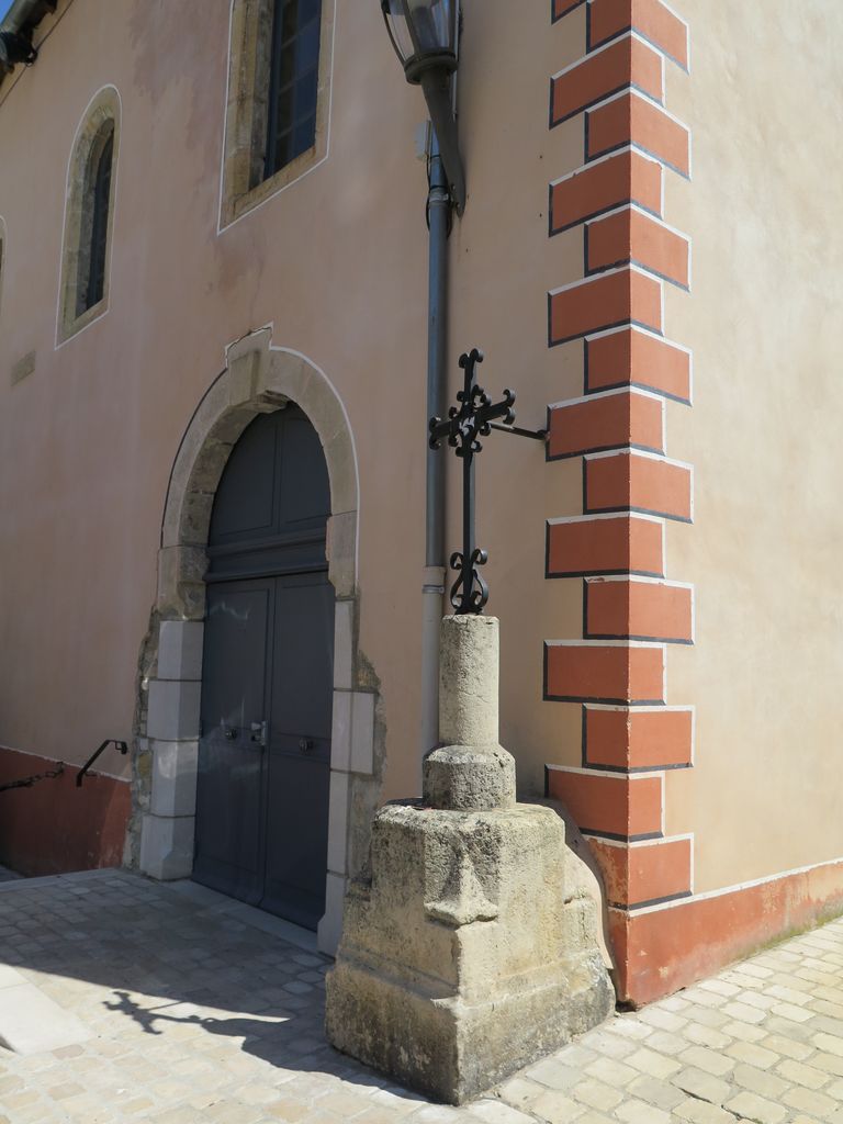 Porte latérale et croix en fer forgé sur socle de pierre sculpté.