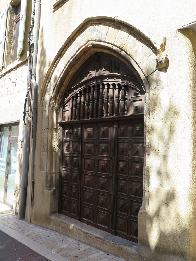 Façade sur rue. Portail gothique et porte en bois à panneaux et balustres.