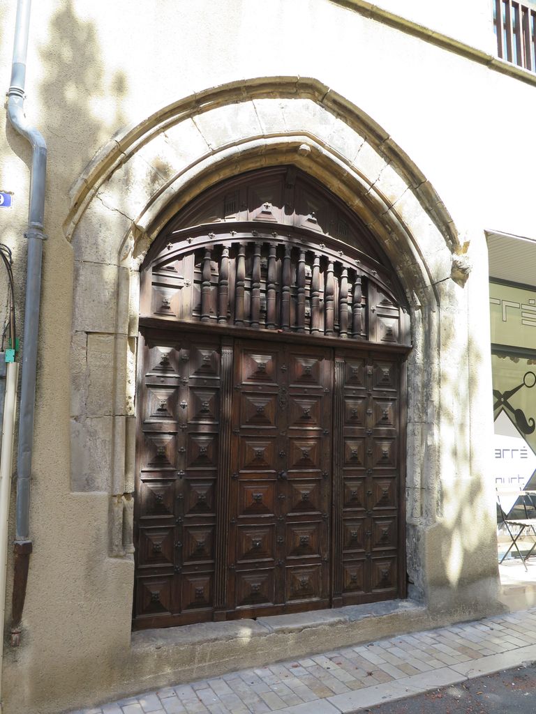 Façade sur rue. Portail gothique et porte en bois à panneaux et balustres.