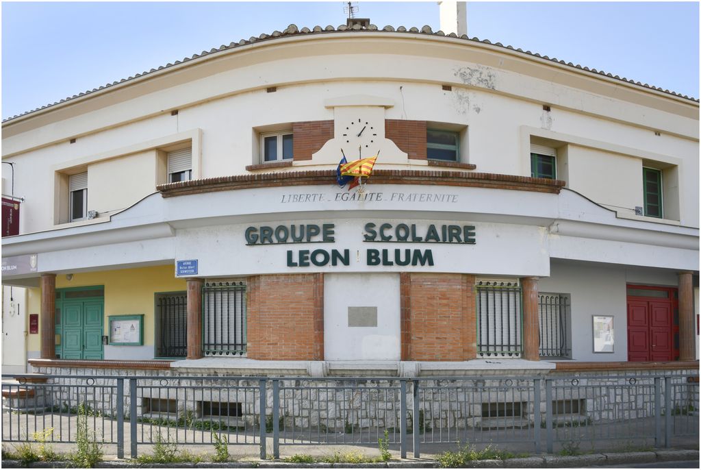 Façade sur rue. Entrée à l’angle des deux ailes. Inscription et horloge.