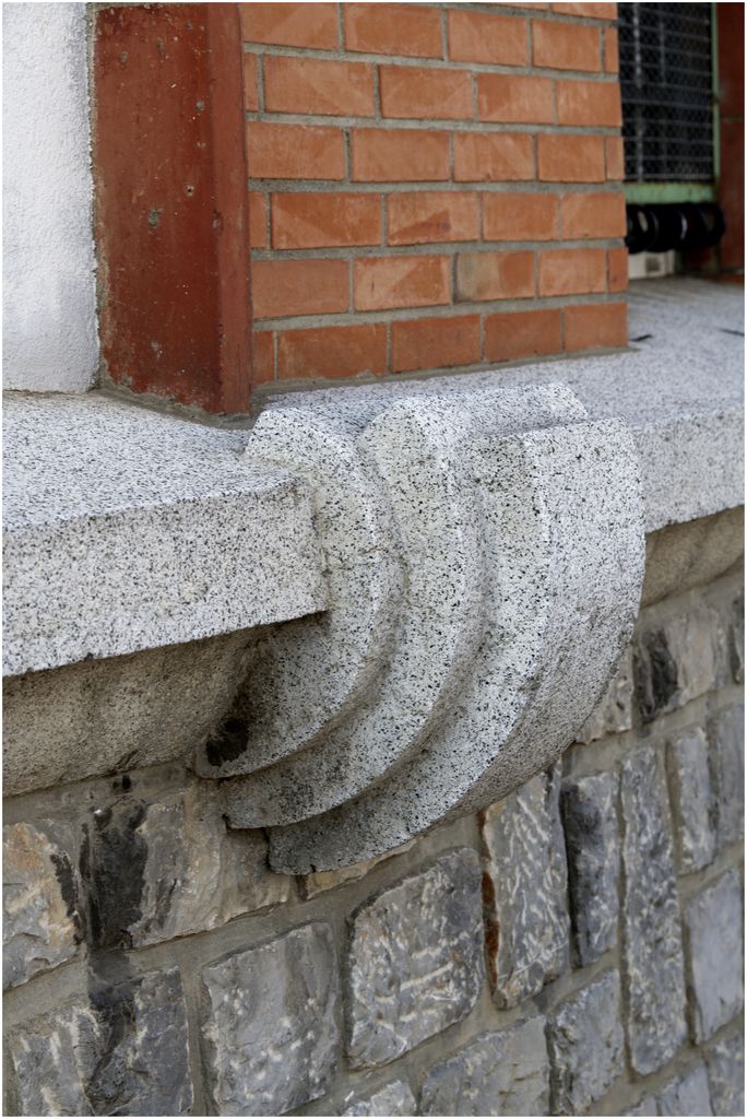 Façade sur rue. Angle des deux ailes. Traitement en pierre du soubassement, en béton du décor et en briques des travées du rdc.