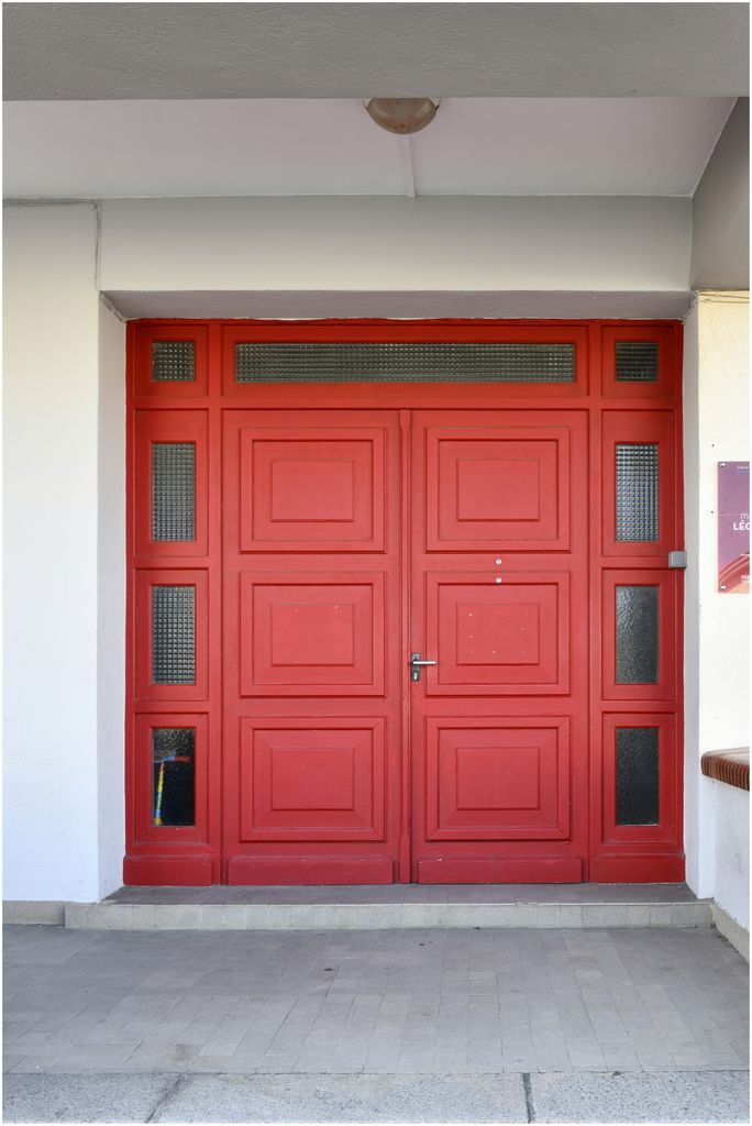 Façade sur rue. Entrée de l’école maternelle. Moellons de pierre et briques aux angles arrondis.