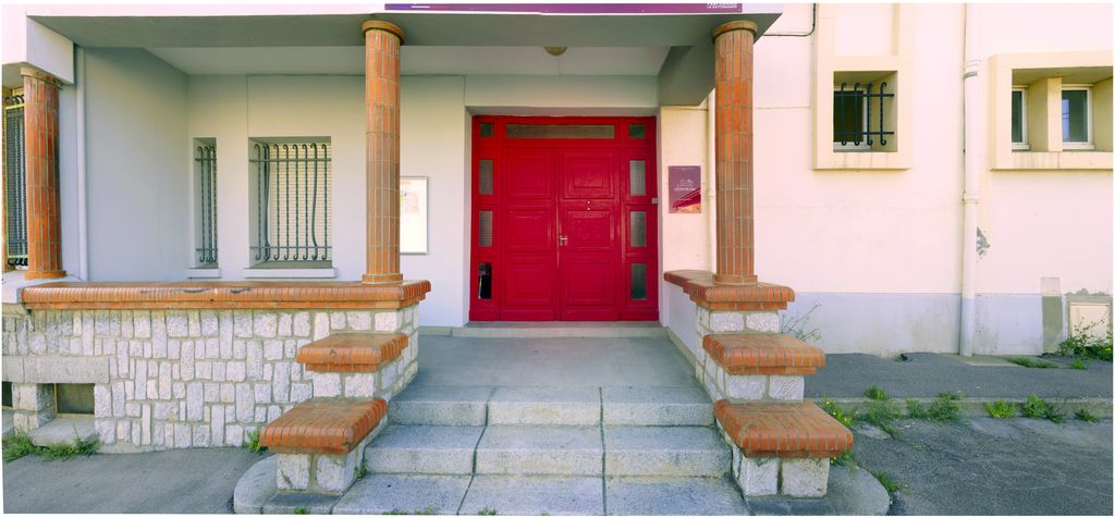 Façade sur rue. Entrée de l’école maternelle. Menuiserie de la porte, bois et verre.