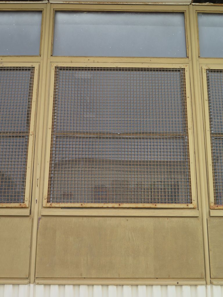 Préfabriqués. Détail façade contreplaqué, tôle et vitrage grillagé.