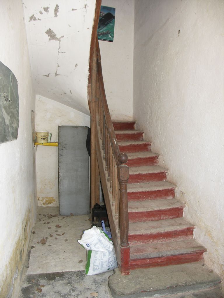 Communs. Cour semi-circulaire des communs. Pavillon du régisseur. Escalier en bois menant à l’étage du logement.