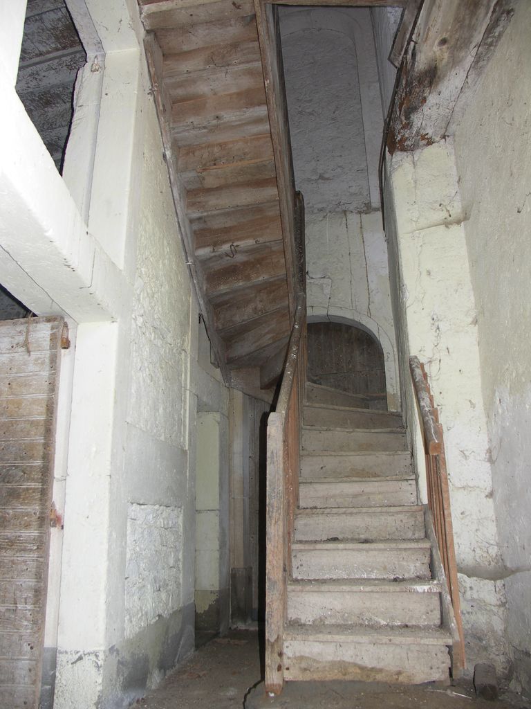 Communs. Cour semi-circulaire des communs. Pavillon du régisseur. Escalier en bois menant à l’étage du logement.