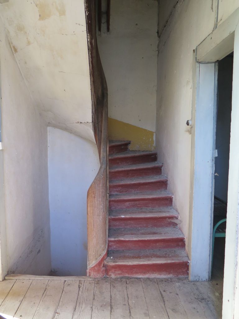 Communs. Cour semi-circulaire des communs. Pavillon du régisseur. Escalier en bois menant à l’étage du logement.