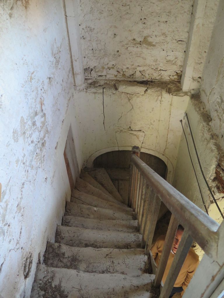 Communs. Cour semi-circulaire des communs. Pavillon du régisseur. Escalier en bois menant à l’étage du logement.