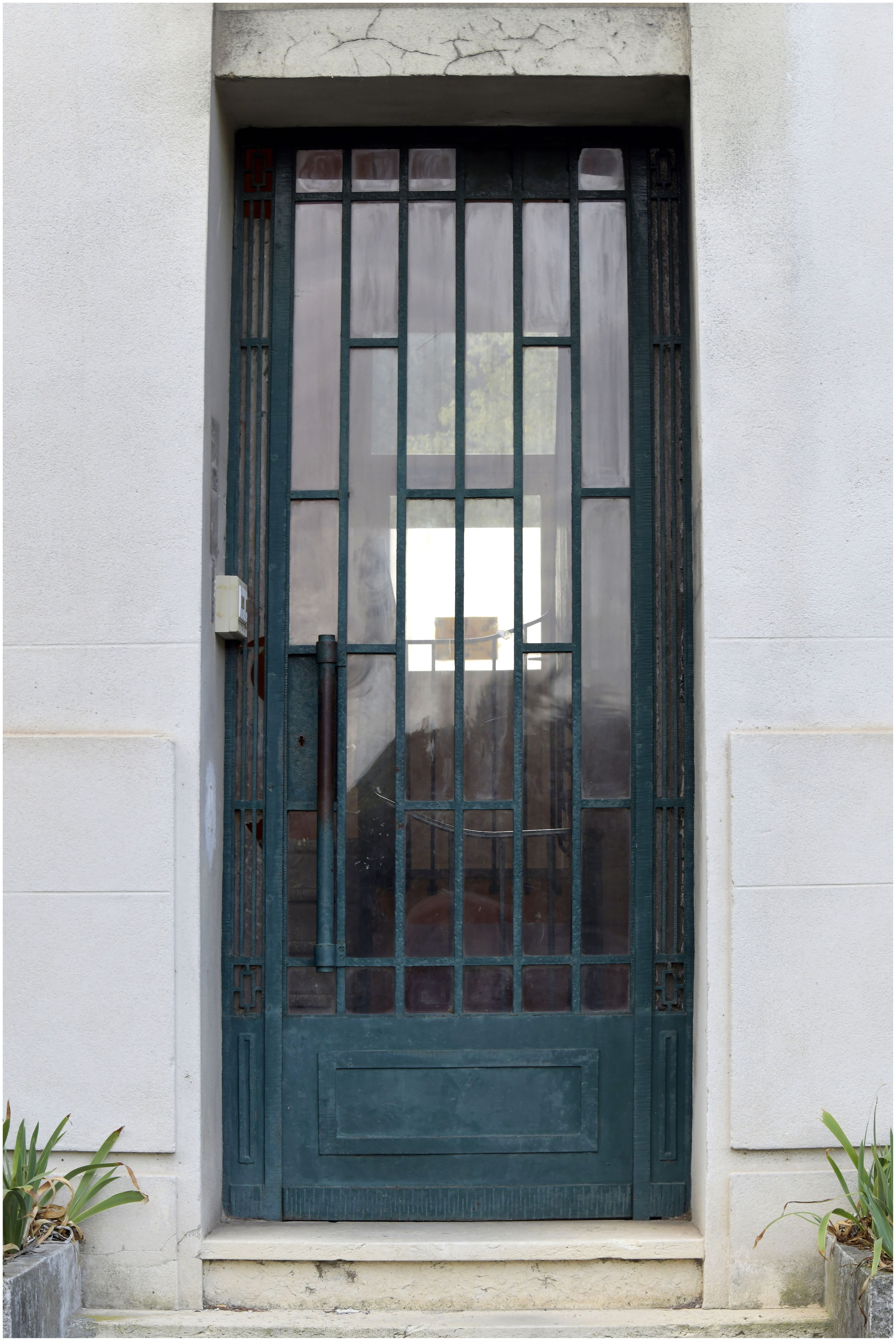 Façade sur la rue. Entrée des logements côté ouest. Détail de la ferronnerie de la porte