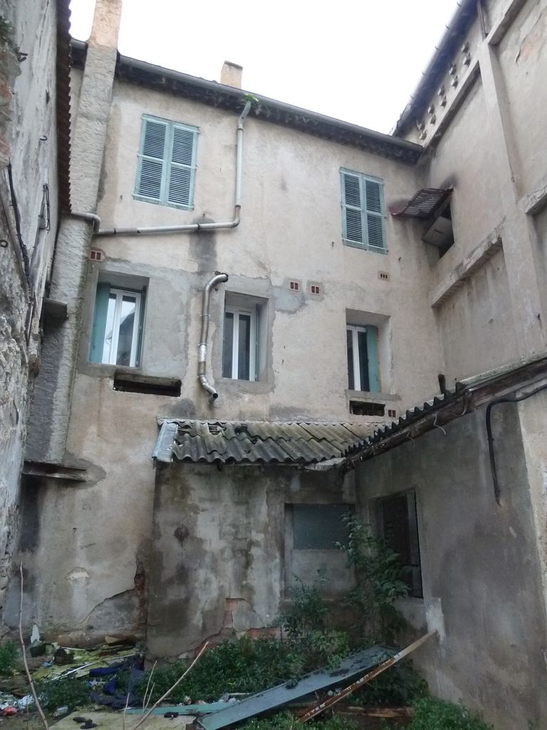 Façade arrière. En cœur d’ilot, résille poteaux poutre en béton armé et remplissage en brique creuse + enduit ciment motifs sous le toit