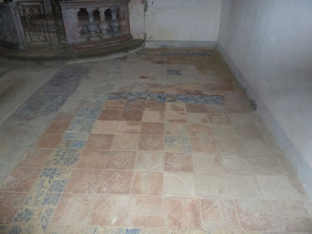 Chapelle. Pavement de briques rouges, marquées en creux d'une tête d'homme coiffée d'un casque à panache 