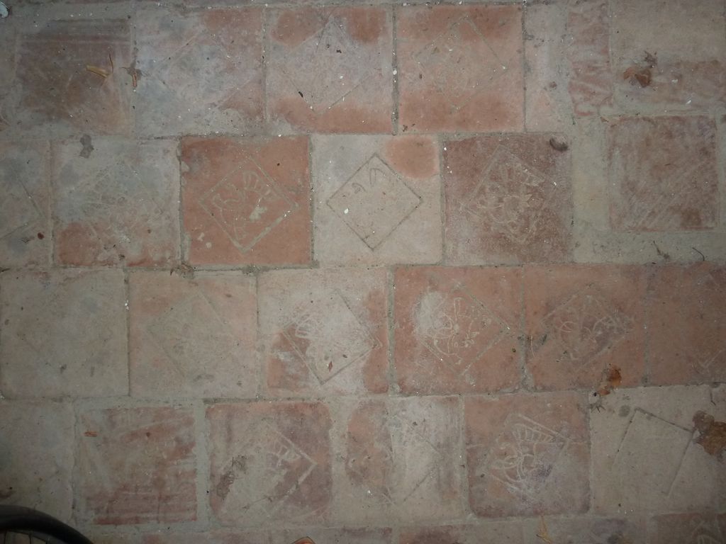 Chapelle. Pavement de briques rouges, marquées en creux d'une tête d'homme coiffée d'un casque à panache 