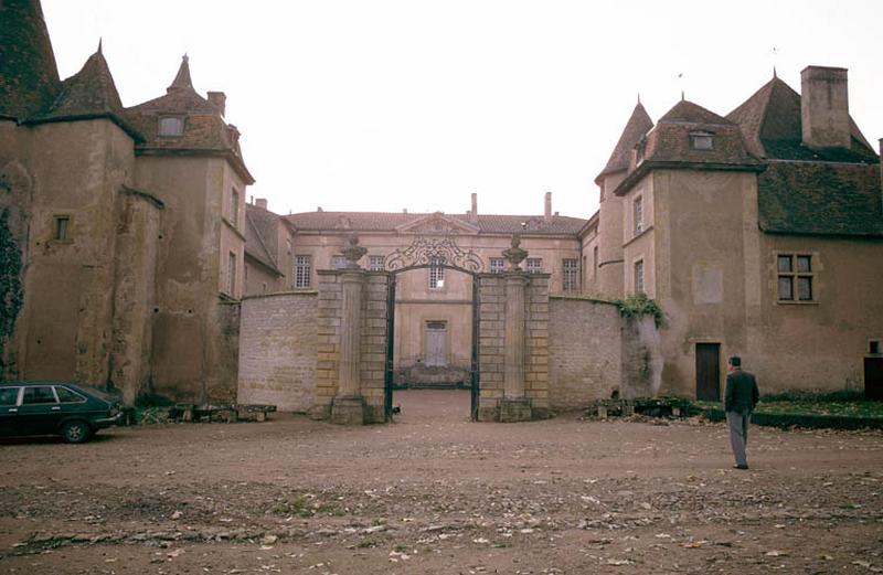 Vue d'ensemble, bâtiments et grille d'entrée en fer forgé.