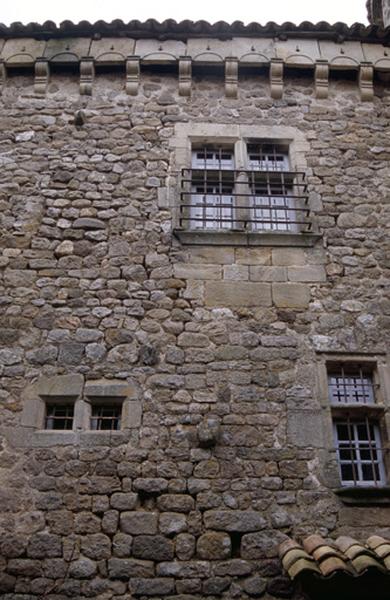 Détail façade, machicoulis et fenêtre bardée de fer.