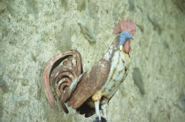 Croix en fer forgé à côté de la porte fortifiée des anciens remparts du Nord-Ouest. Détail du coq.