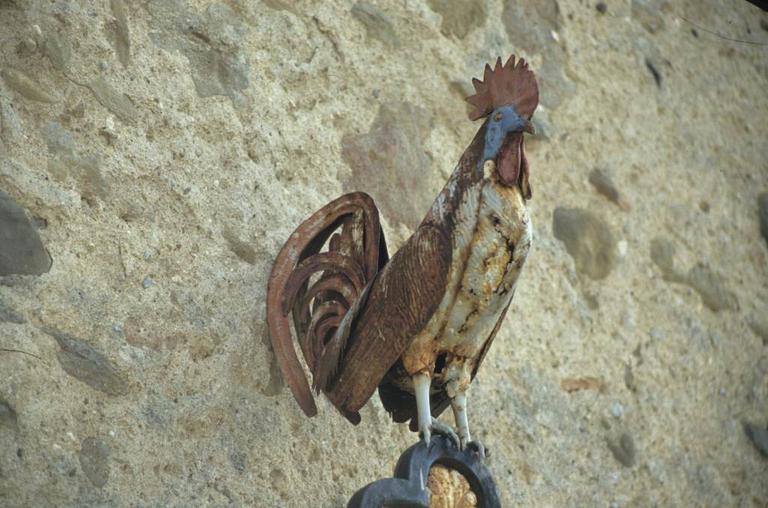 Croix en fer forgé à côté de la porte fortifiée des anciens remparts du Nord-Ouest. Détail de la partie haute. Le coq en fer forgé peint.