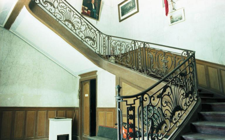 Cage d'escalier avec sa rampe en fer forgé.