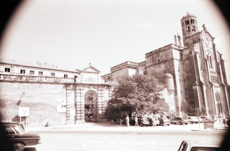 Clôture de la cour d'honneur avec le portail d'entrée et l'ancienne cathédrale.