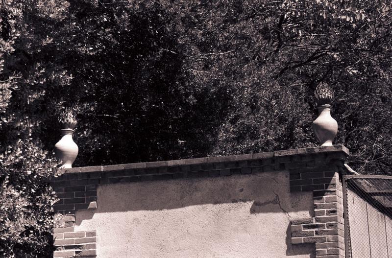 Détail de sculpture (pots à feu) sur mur de clôture.