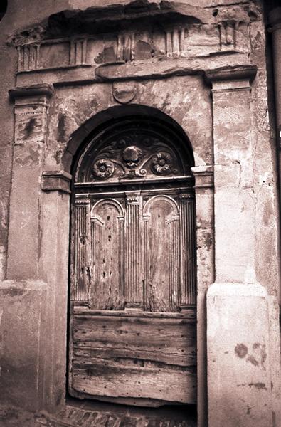 Porte à pilastres et entablement, menuiserie de porte présentant également des pilastres cannelés.