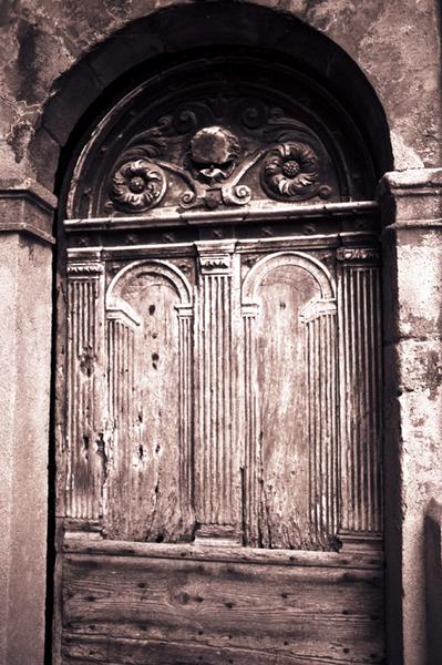 Porte à pilastres et entablement, menuiserie de porte présentant également des pilastres cannelés.