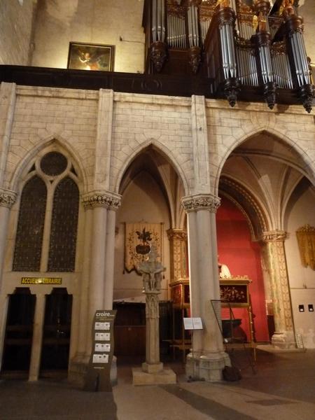 Sous la tribune : la croix en pierre classée, qui se trouvait autrefois dans l'ancien cimetière. Le fût d'origine n'a pas été conservé, la croix a été placée sur un fût et un socle refaits, quand elle a été déplacé au fond de l'église sous la tribune.