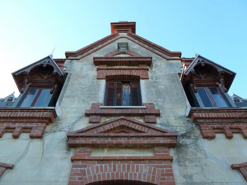 Façade est : toit d'ardoises, cordons de briques, lucarnes en bois.