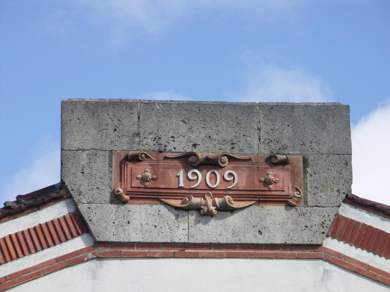 Fronton du chai de conservation de 1909, date portée sur un cartouche en terre cuite.